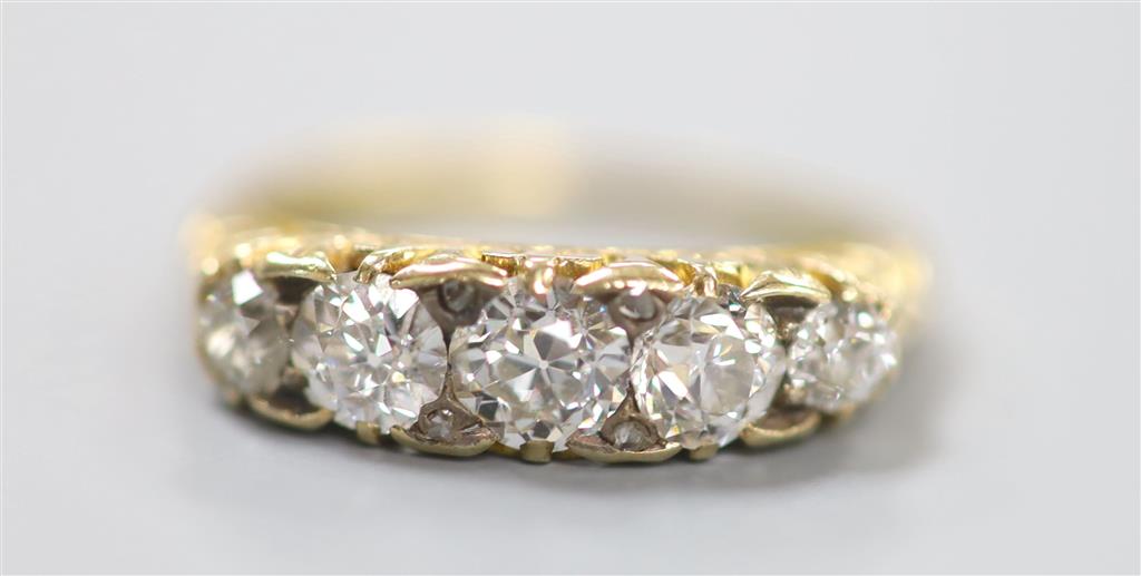 An early 20th century yellow metal and graduated five stone diamond set half hoop ring, size N, gross 3.6 grams.